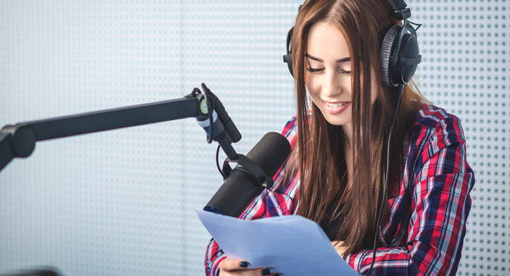 Una chica leyendo un guión de podcast ante un micrófono